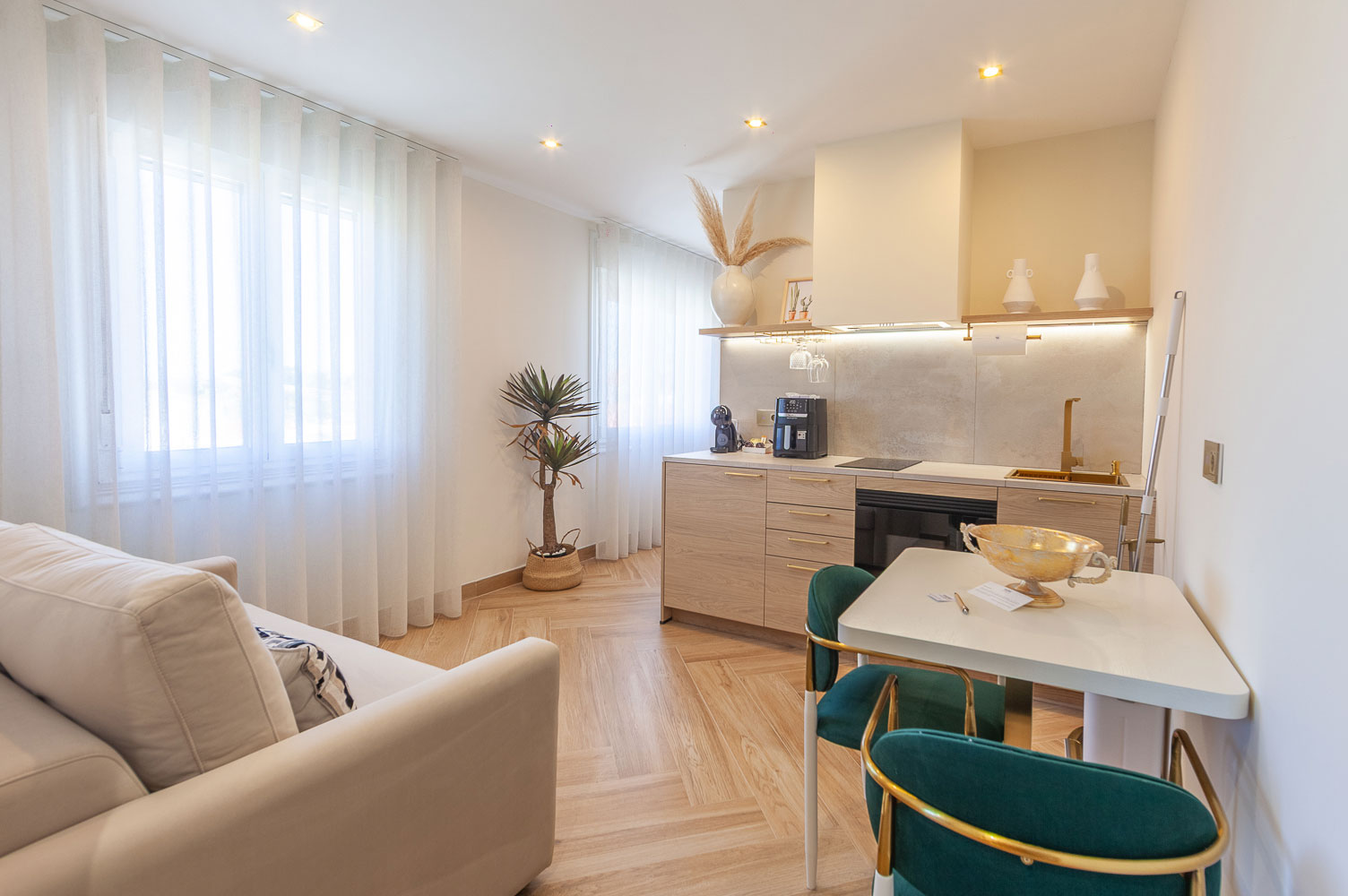 cocina/comedor con unas sillas en verde terciopelo y detalles dorados. Vista de unos de los apartamentos de WOW Baiona