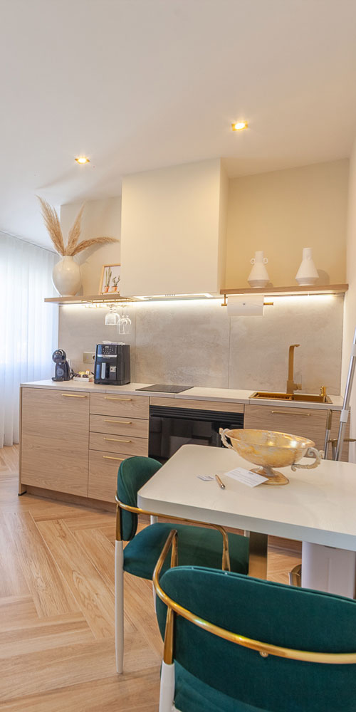 cocina/comedor con unas sillas en verde terciopelo y detalles dorados. Vista de unos de los apartamentos de WOW Baiona